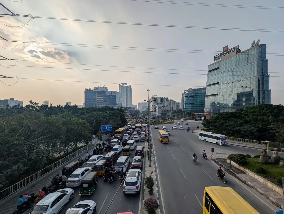 Archived elevated photograph of a busy service-road junction facing Nanakramguda, with buildings, traffic, road edges and central planting.